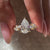 Yellow gold engagement ring with a pear center diamond and round side stones.
