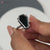 Black moissanite ring set in a coffin ring design for bold elegance.
