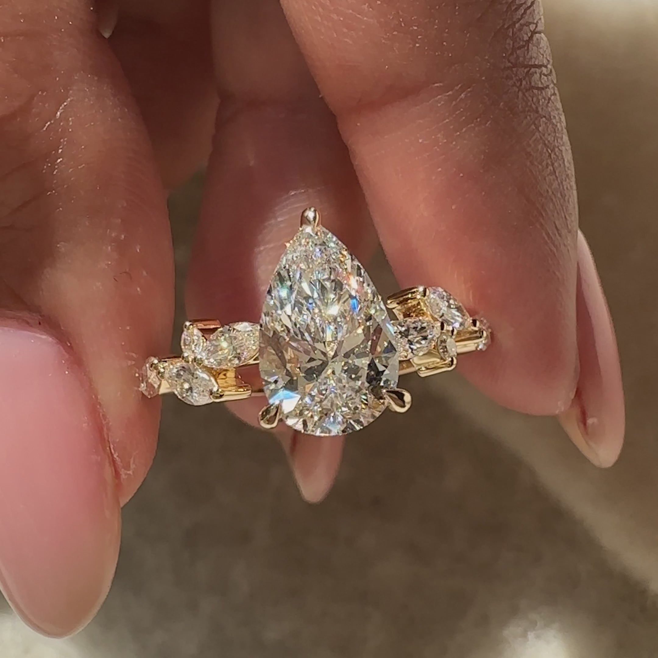 Yellow gold engagement ring with a pear center diamond and round side stones.
