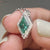 Lozenge cut pendant with a halo design, crafted in white gold.
