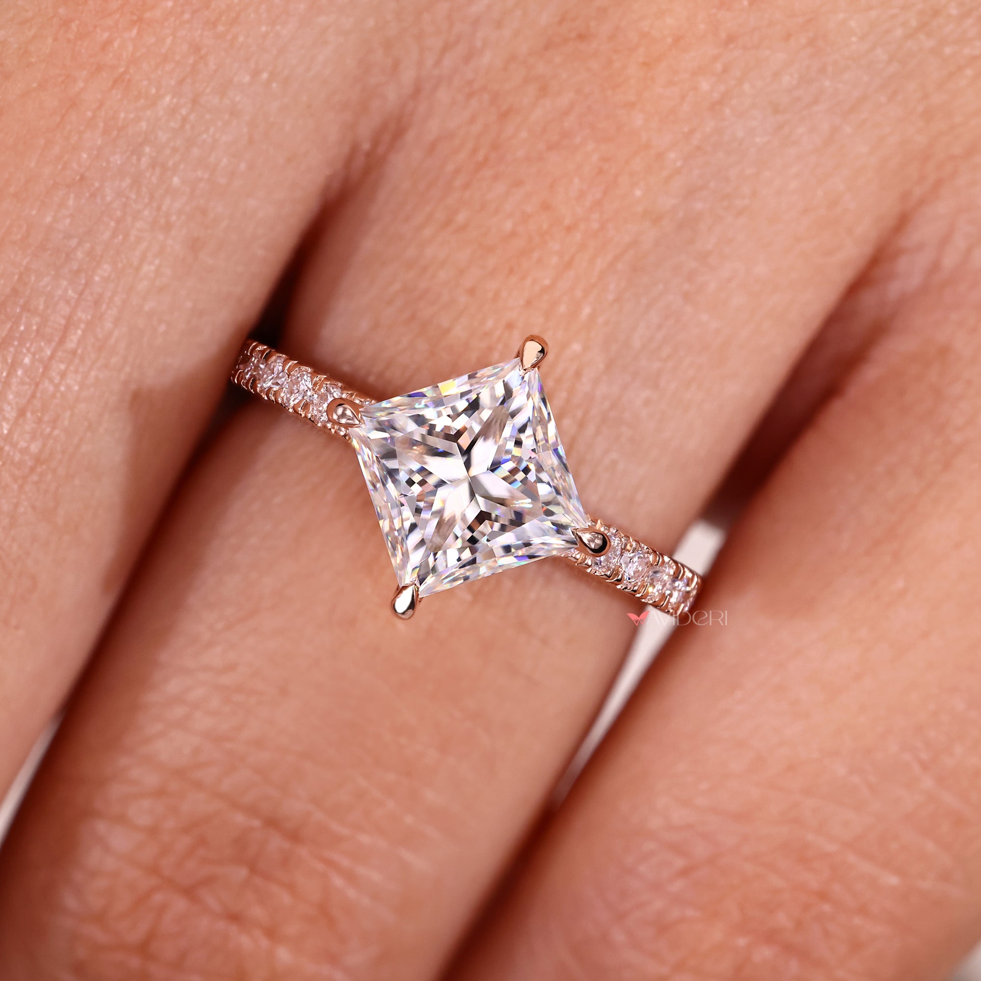 Fine jewelry engagement ring with princess cut moissanite and pave stones.