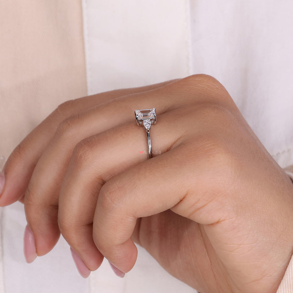 Engagement rings pear shaped side stones with a three stone emerald cut diamond ring design for timeless sophistication.
