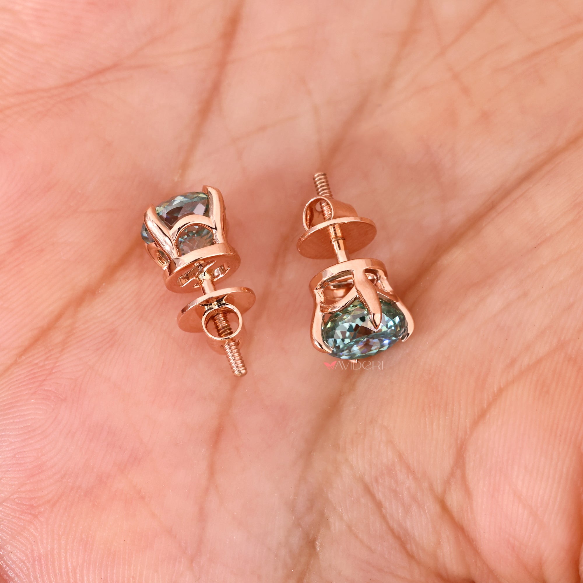 Rose gold moissanite earrings with cyan blue stones.