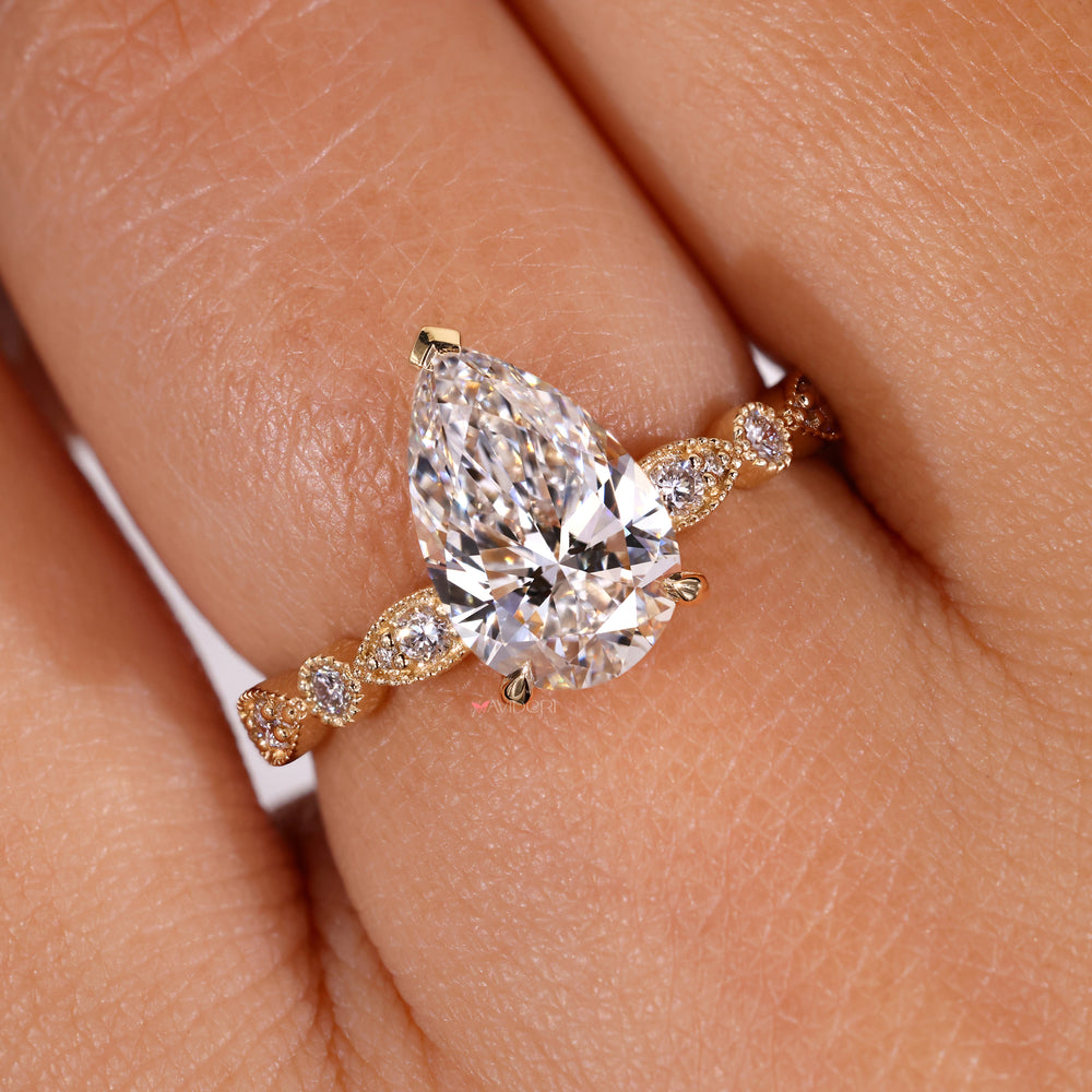 Milgrain engagement ring with intricate detailing surrounding the pear shaped diamond.
