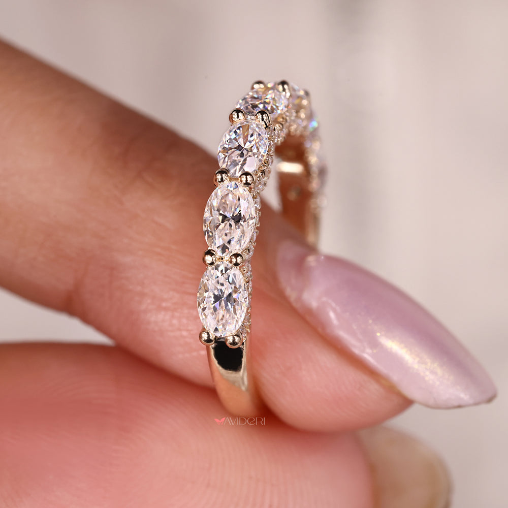 Oval cut wedding band with lab-created moissanite in a shared prong yellow gold design.