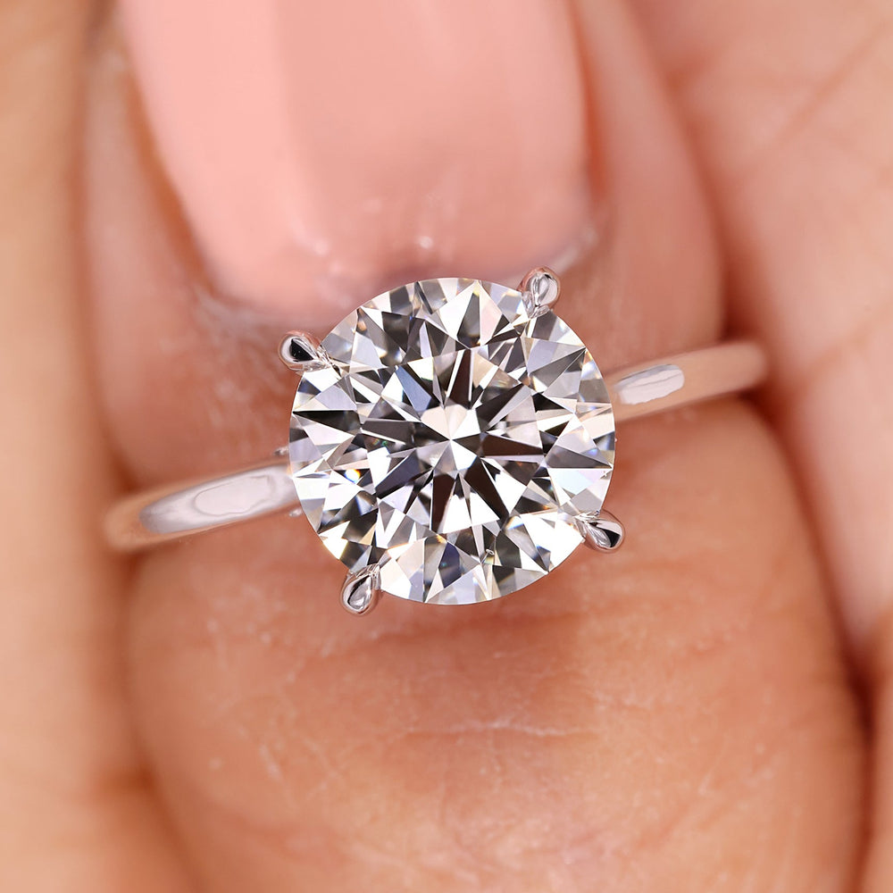 Round diamond ring with four prong setting and bridge accent.