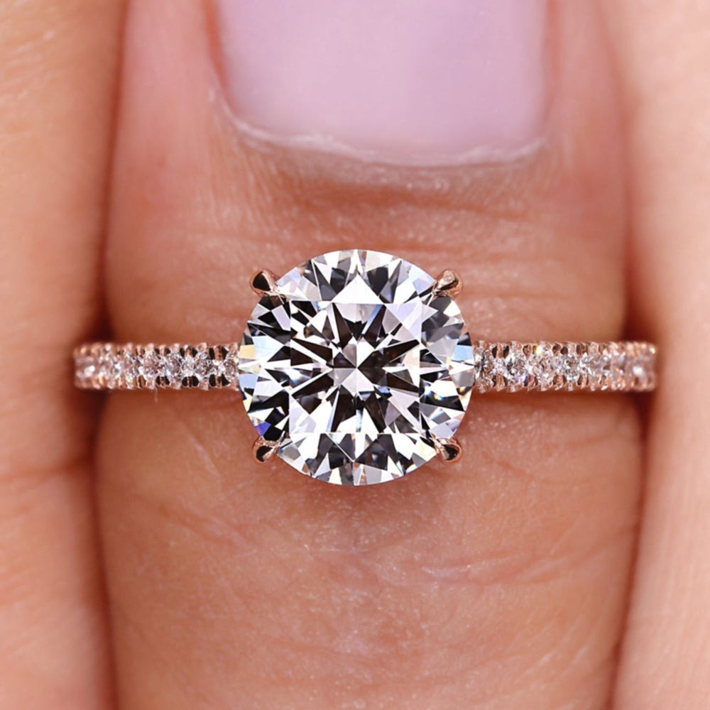 Round diamond engagement ring featuring a round diamond pave band and four claw prong setting.
