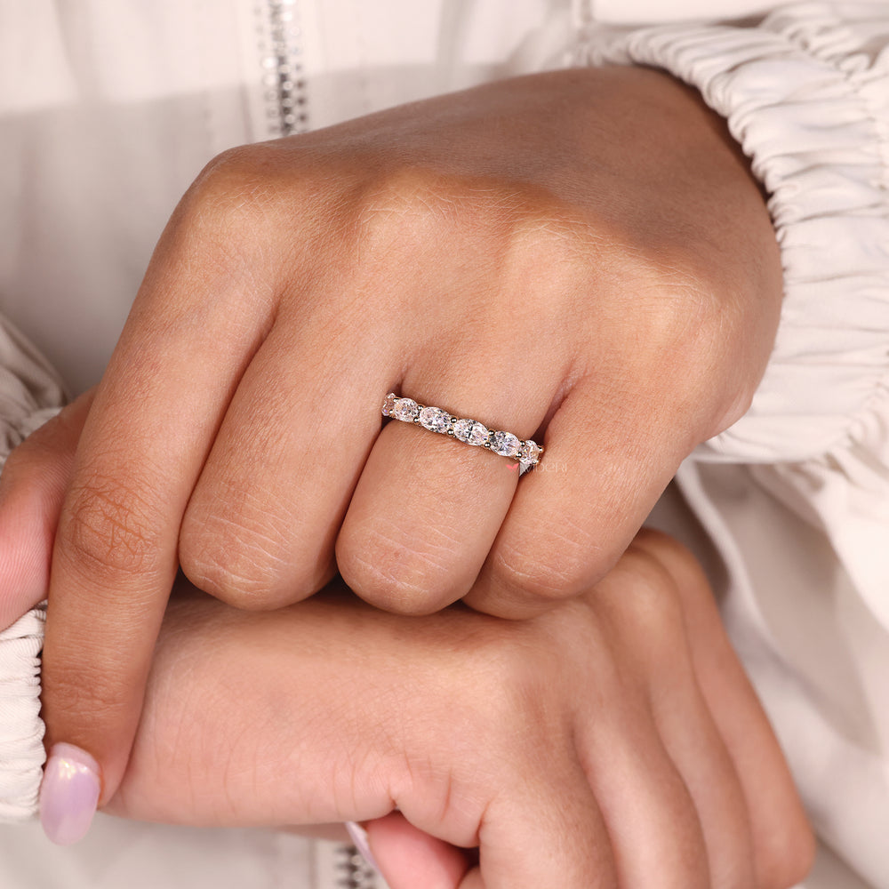 Shared prong wedding band featuring oval moissanite and micro pave round accents.