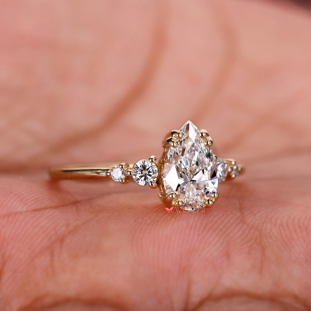 Pear shape diamond and four round diamonds with side stones crafted into a stunning handmade jewelry design.
