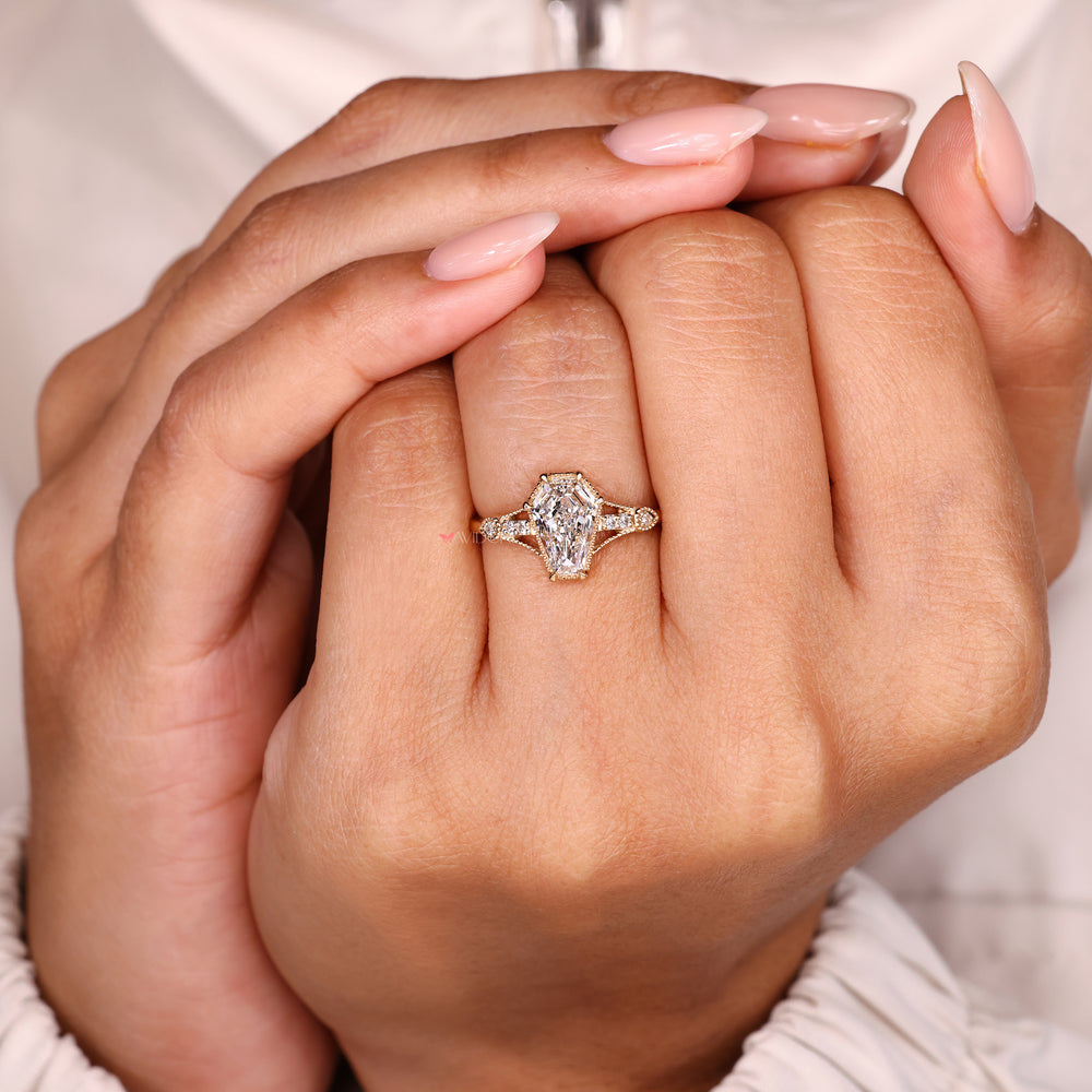 Shield cut diamond ring with round side stone accents.
