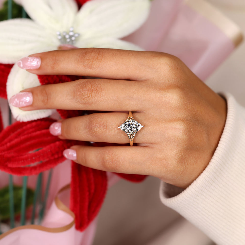 Marquise cut diamond ring with ornate scroll design.
