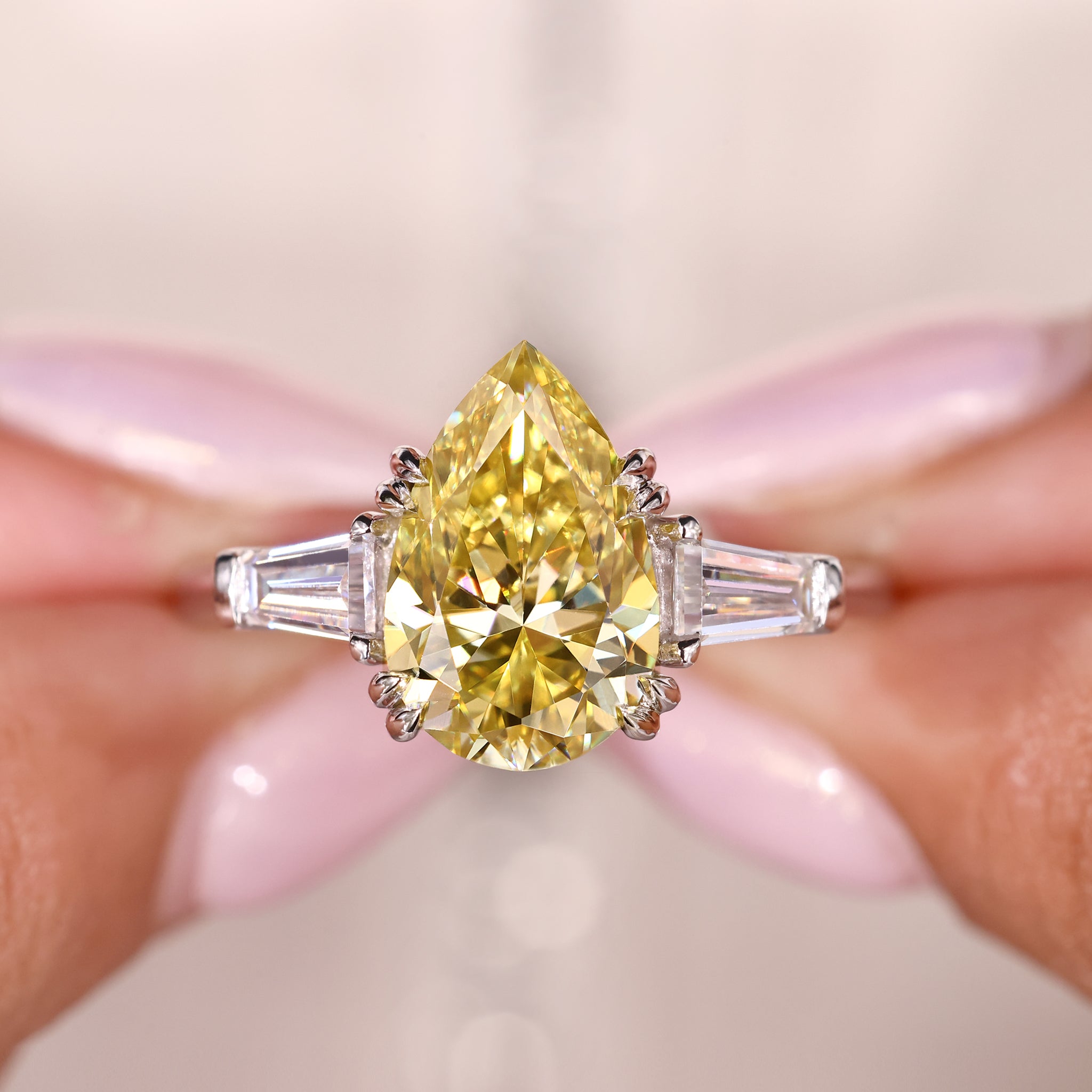 Three stone moissanite ring with Canary Yellow pear cut center and tapered baguette side stones.
