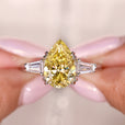 Three stone moissanite ring with Canary Yellow pear cut center and tapered baguette side stones.
