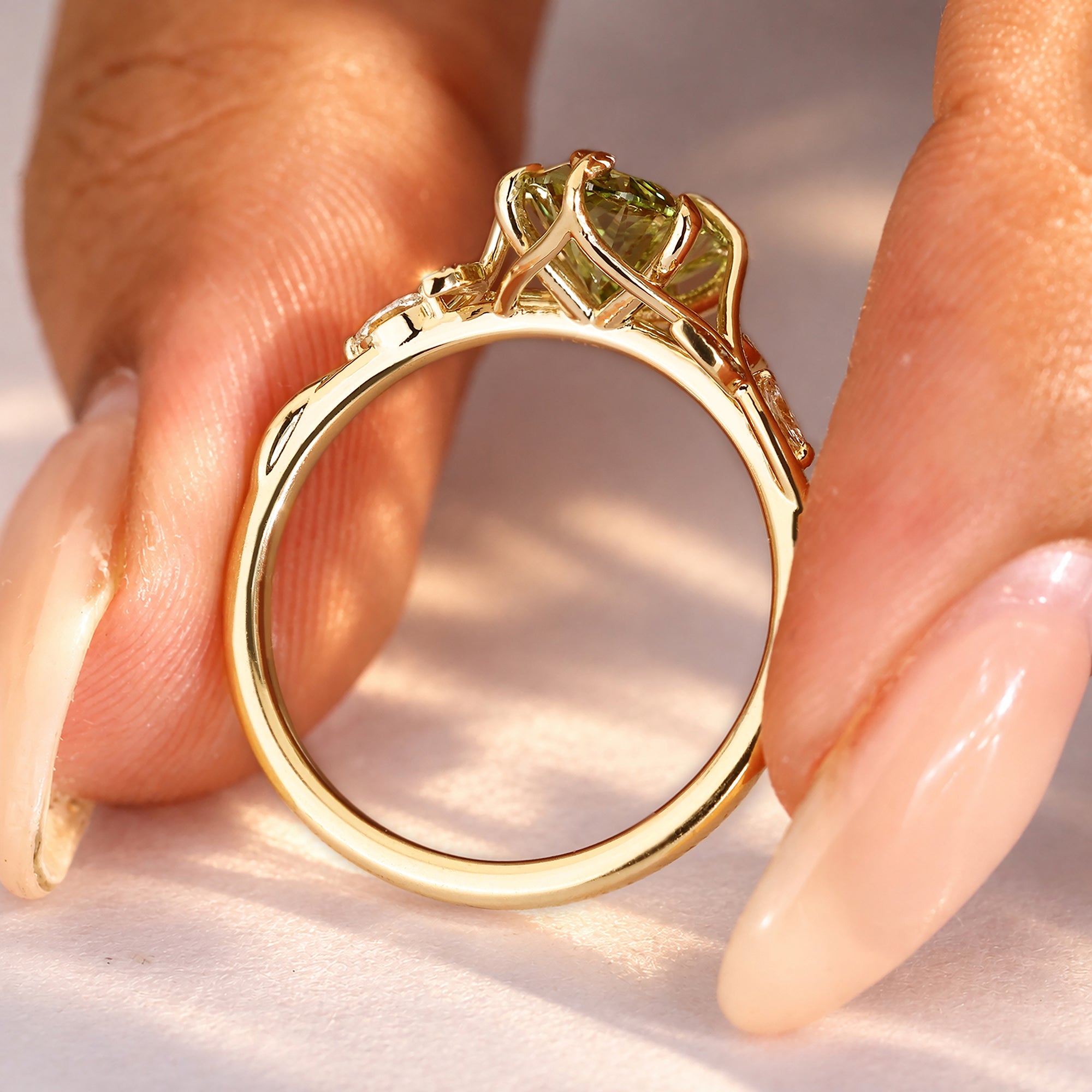 Oval green diamond ring with four leaf claw prongs.