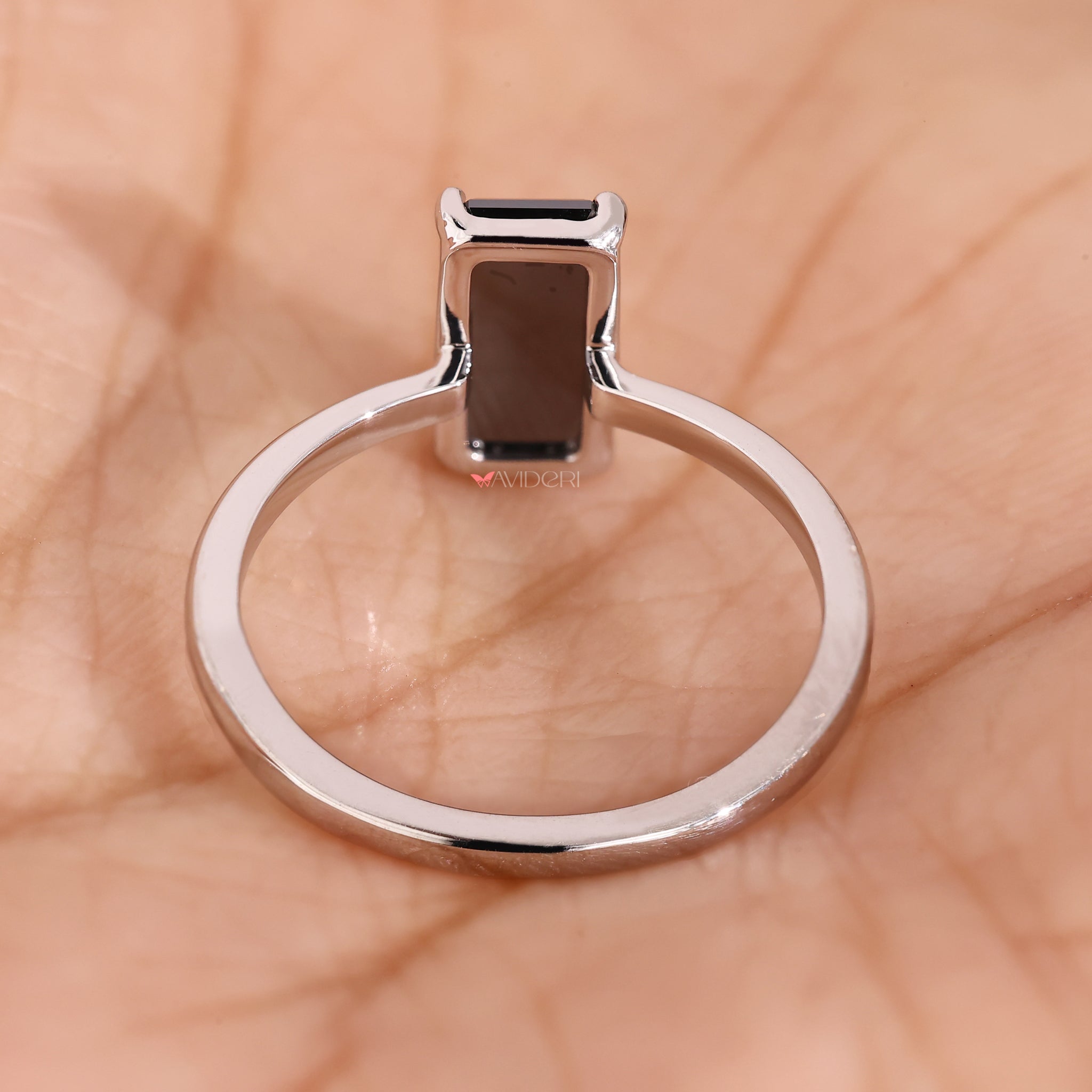 White gold engagement ring with a bold emerald portrait cut center.