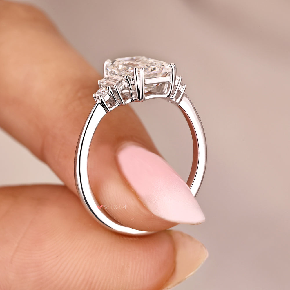 Emerald cut five stone diamond ring with tapered shank.
