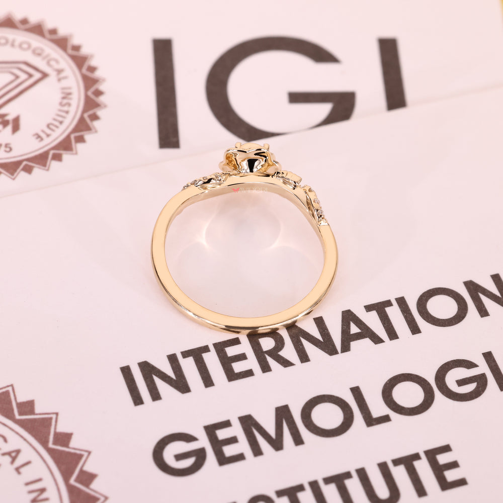 Yellow gold floral engagement ring with a brilliant round diamond and pavé leaf accents.