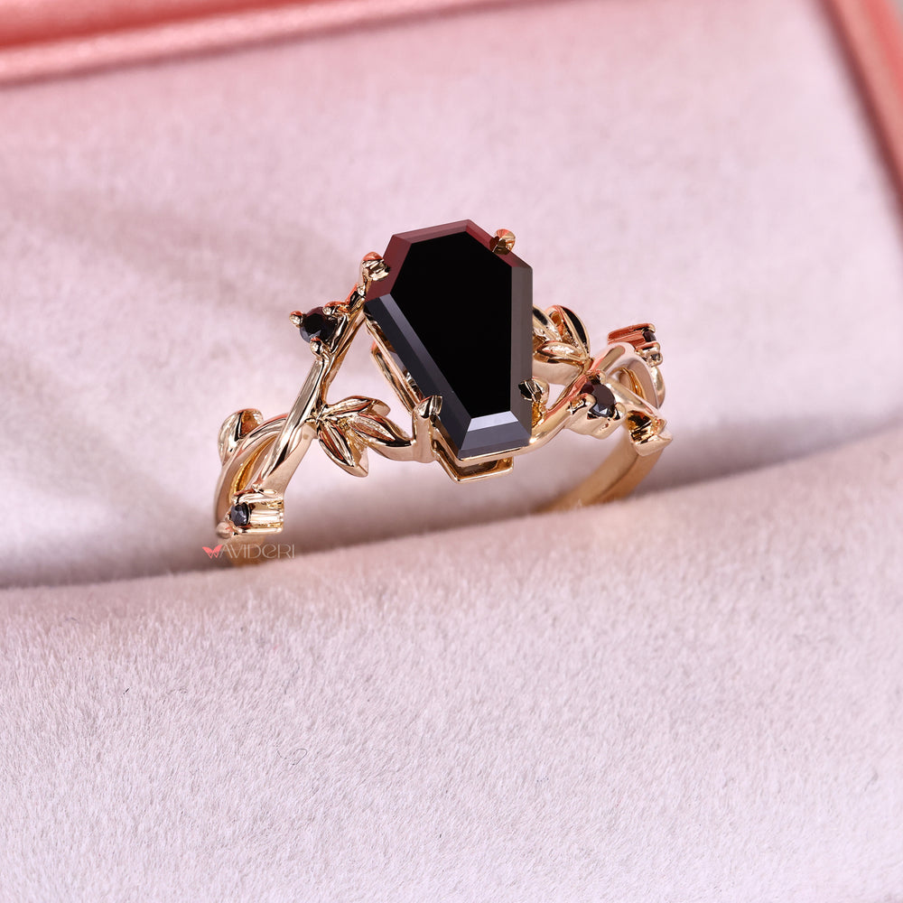 Gold ring with a black moissanite on a pink surface